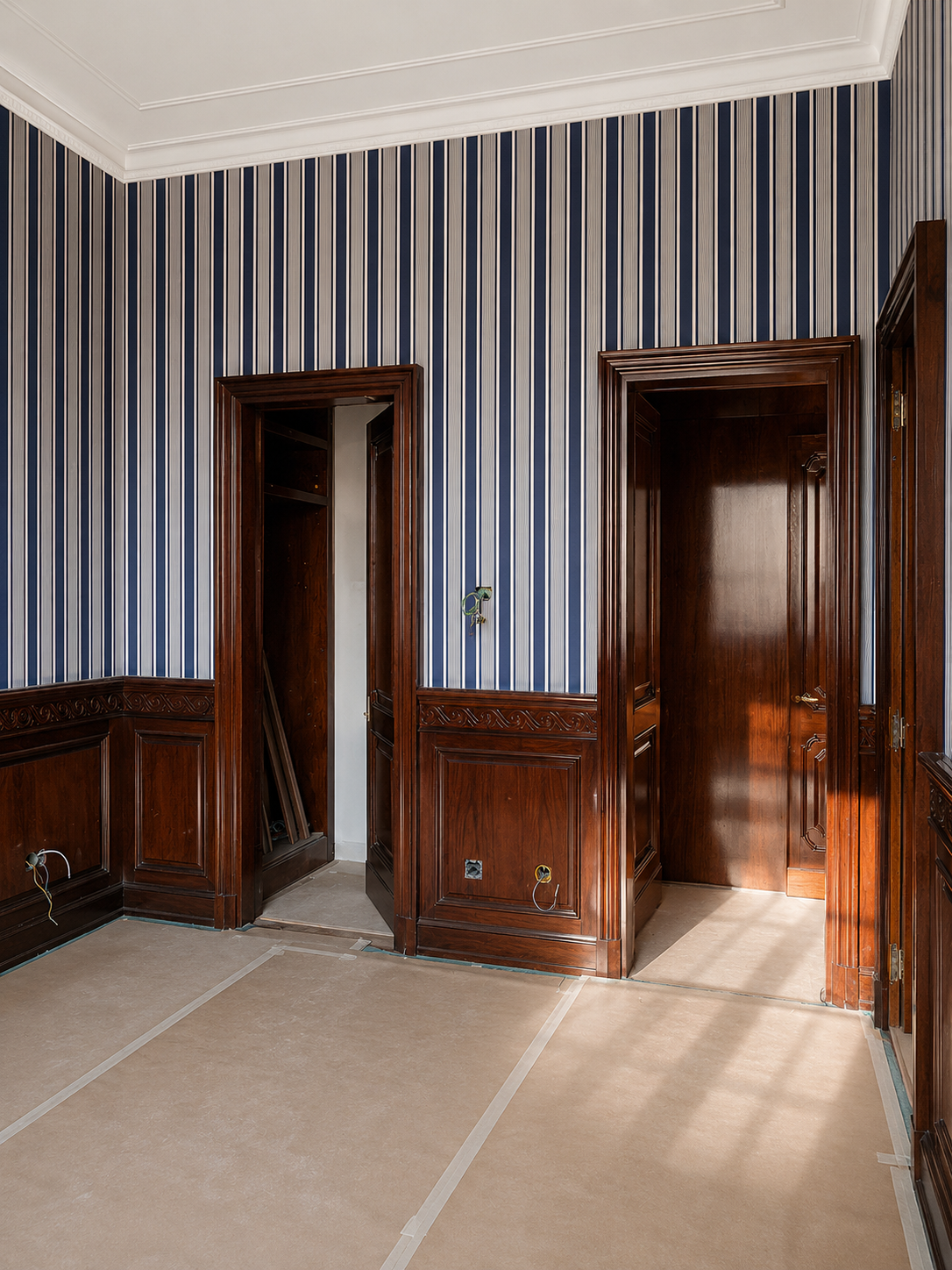 Mahogany joinery and doors installed on-site; brand wallpaper applied, flooring works ongoing